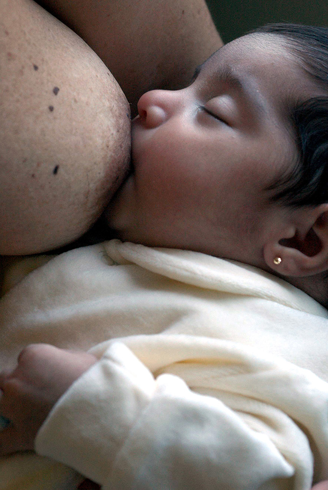 Foto de um bebê sendo amamentado.