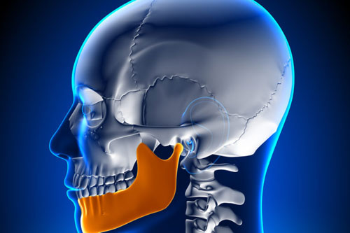  Ilustração de um crânio humano, destacando a mandíbula em uma tonalidade de laranja vibrante.