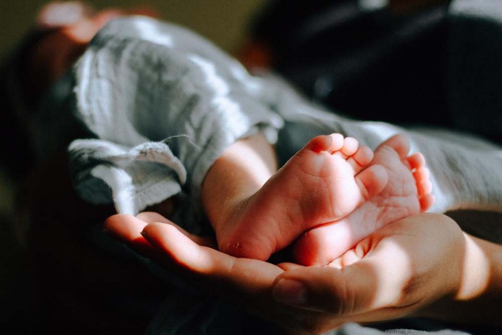 Pessoa segurando os pés de um bebê.