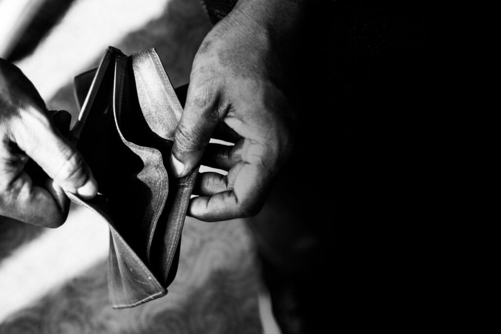 Fotografia em preto e branco de uma mão segurando uma carteira vazia.