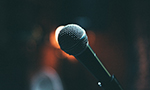 Photograph of a microphone on a dark background.
