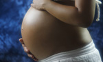 Photograph of a pregnant woman with hands on her belly.
