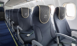 Photograph of the interior of an airplane, showing the blue seats arranged along the cabin.