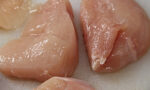 Photo of raw chicken breasts on a white board