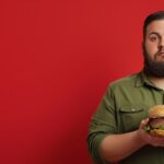 Red background image of a man holding a hamburger.