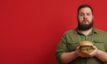 Red background image of a man holding a hamburger.