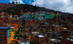 Colorful hillside neighborhood with densely packed brick buildings and a cable car line crossing above.