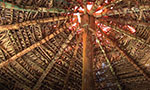 Foto: teto de palha de construção indígena com uma viga de madeira no meio.