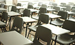 Foto: uma sala de aula com várias cadeiras vazias.