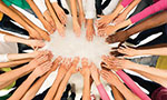 Um grupo de pessoas em roda com as mãos estendidas entre elas dando a ideia de união e trabalho em equipe.