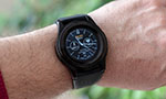 Foto: relógio inteligente no pulso de uma pessoa. Material preto, visor analógico, contagem de passos e de batimentos cardíacos.