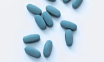 Pílulas azuis espalhadas sobre um fundo branco.