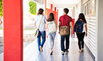 Foto de banco de imagens. Vista traseira de um grupo de estudantes universitários se afastando no corredor da escola.