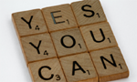 Peças de um jogo word board, sobre um fundo branco, formando a frase "yes, you can" (sim, você pode).