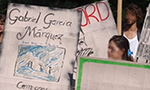 Pessoas segurando grandes placas que simulam capas de livros. As duas placas em maior evidência na fotografia fazem referência às obras "Cem anos de solidão", de Gabriel García Márquez, e “Pedagogia do Oprimido”, de Paulo Freire.