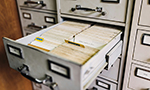 Gaveta de arquivo aberta com fichas organizadas e separadas por abas visíveis, mostrando uma disposição ordenada de documentos.