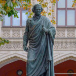 fotografia do monumento a Schelling na Maximiliansstraße, em frente ao prédio do governo. Erigido em 1861 "por seu grato aluno Maximiliano II, Rei da Baviera" ao filósofo falecido em 1854.