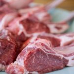 Fotografia de vários pedaços de carne crus colocados em uma superfície. A fotografia foca apenas em um dos pedaços