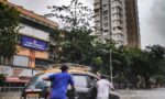 Fotografia de dois homens empurrando um carro preio em meio a uma enchente.